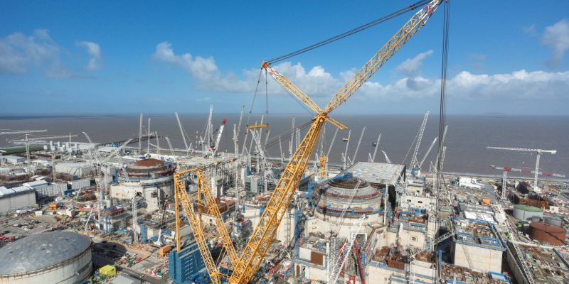 Hinkley Point C nuclear construction with the iconic "Big Carl" crane sweeping over the reactor containment domes — same EPR design now committed at Sizewell C following 2025 FID.